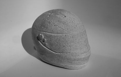 left side angle of custom-made mini Formula 1 helmet designed with a concrete grey finish, ideal for industrial-style home decor. The helmet, crafted to resemble polished concrete with a matte texture, offers a robust and stylish addition to any modern space. Available for purchase with customization options on the website.