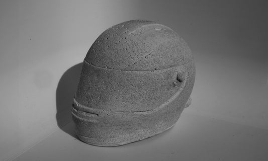 Left side angle of custom-made mini Formula 1 helmet designed with a concrete grey finish, ideal for industrial-style home decor. The helmet, crafted to resemble polished concrete with a matte texture, offers a robust and stylish addition to any modern space. Available for purchase with customization options on the website.