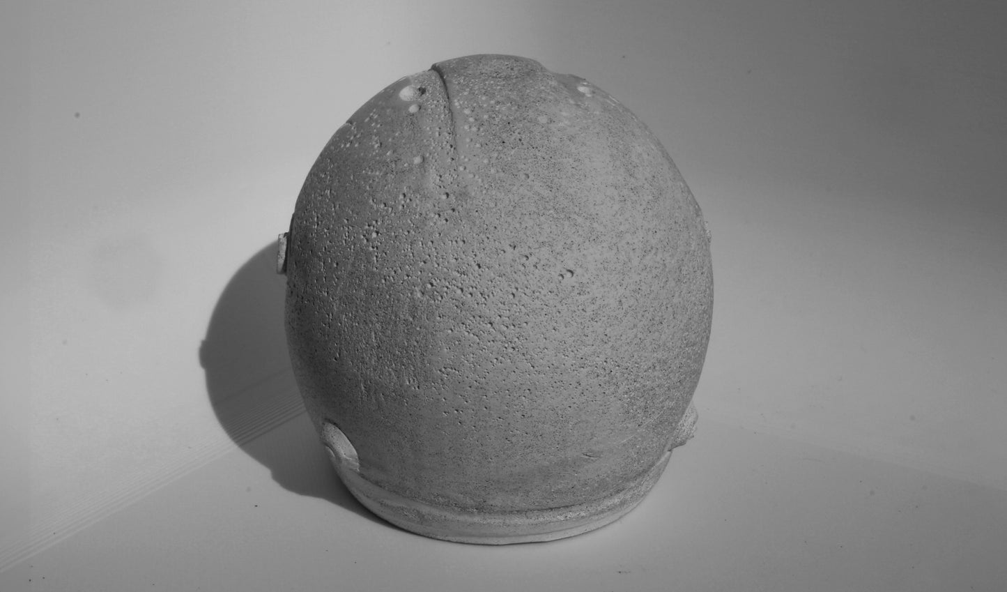 Back angle of custom-made mini Formula 1 helmet designed with a concrete grey finish, ideal for industrial-style home decor. The helmet, crafted to resemble polished concrete with a matte texture, offers a robust and stylish addition to any modern space. Available for purchase with customization options on the website.