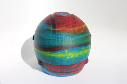 Back angle of Custom-made concrete mini Formula 1 helmet designed with vibrant red, blue, and yellow colors, resembling a galaxy theme. The helmet, crafted from concrete/Jesmonite, showcases intricate details and a glossy finish, reflecting the cosmos. Available for purchase with customization options on the website.