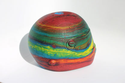 Left side angle of Custom-made concrete mini Formula 1 helmet designed with vibrant red, blue, and yellow colors, resembling a galaxy theme. The helmet, crafted from concrete/Jesmonite, showcases intricate details and a glossy finish, reflecting the cosmos. Available for purchase with customization options on the website.