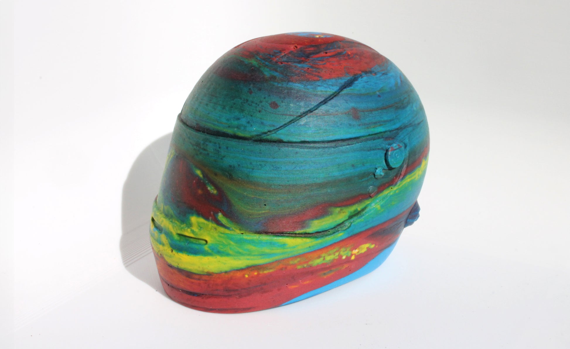 Right side angle of Custom-made concrete mini Formula 1 helmet designed with vibrant red, blue, and yellow colors, resembling a galaxy theme. The helmet, crafted from concrete/Jesmonite, showcases intricate details and a glossy finish, reflecting the cosmos. Available for purchase with customization options on the website.