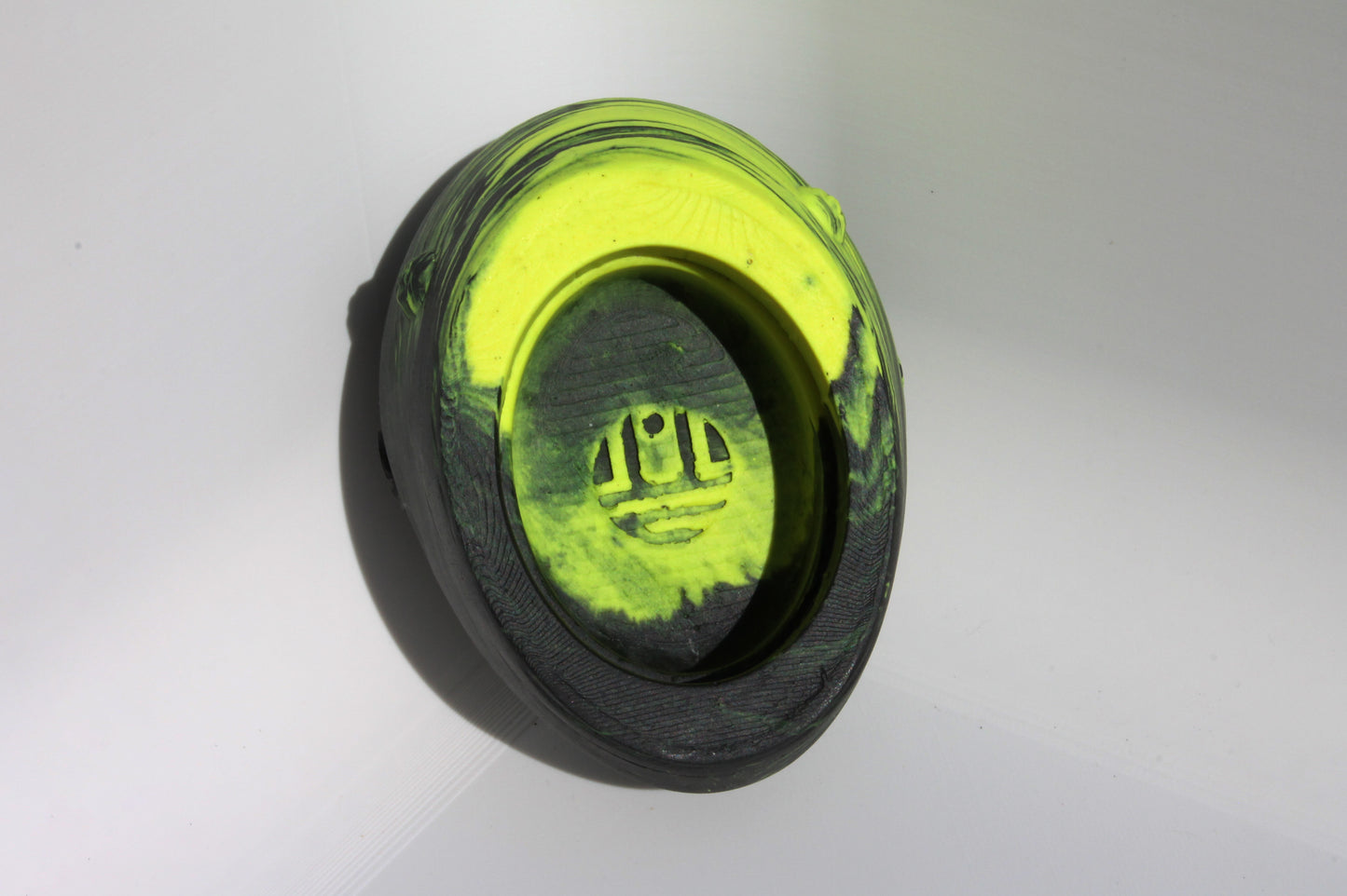 Bottom angle of custom-made concrete mini Formula 1 helmet designed with striking neon yellow and black colors, inspired by Lando Norris. The helmet, crafted from concrete/Jesmonite, showcases intricate details and a sleek finish. Available for purchase with customization options on the website.