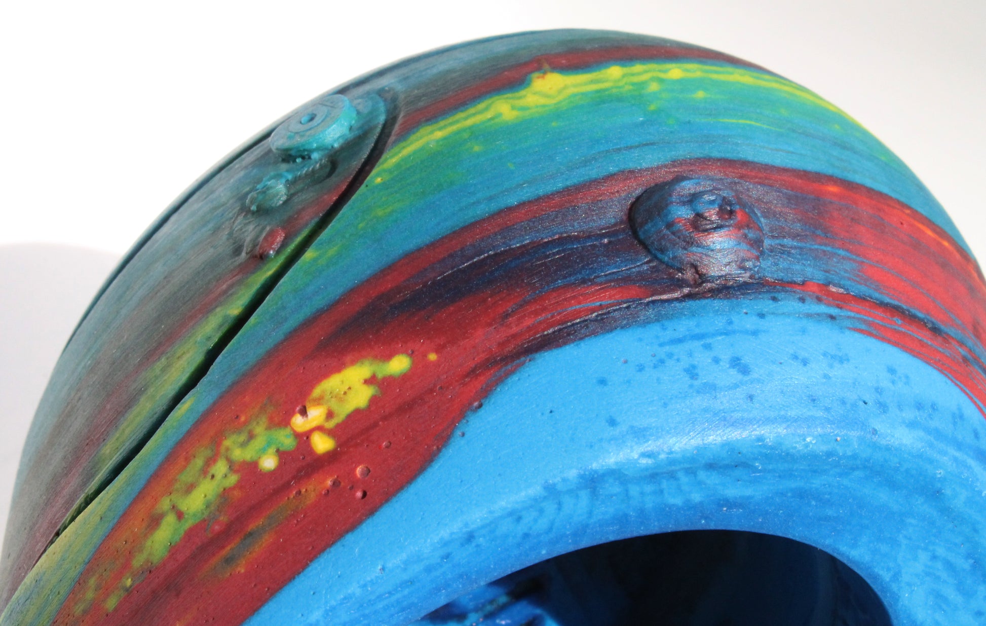 on its side angle of Custom-made concrete mini Formula 1 helmet designed with vibrant red, blue, and yellow colors, resembling a galaxy theme. The helmet, crafted from concrete/Jesmonite, showcases intricate details and a glossy finish, reflecting the cosmos. Available for purchase with customization options on the website.