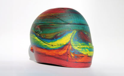 Front side angle of Custom-made concrete mini Formula 1 helmet designed with vibrant red, blue, and yellow colors, resembling a galaxy theme. The helmet, crafted from concrete/Jesmonite, showcases intricate details and a glossy finish, reflecting the cosmos. Available for purchase with customization options on the website.